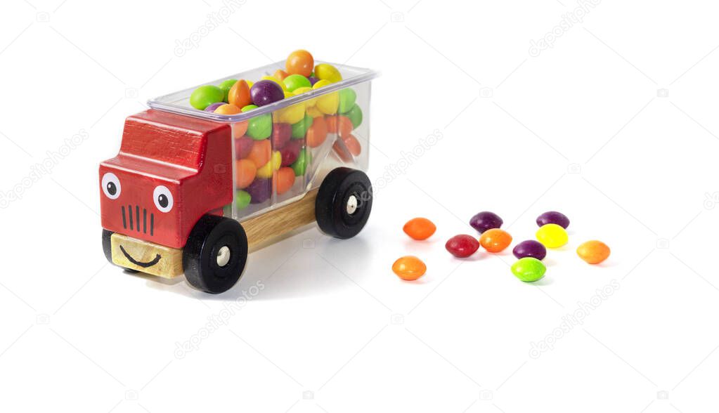 multi-colored candies fell from the back of a red childrens toy car. Candy boom. White background