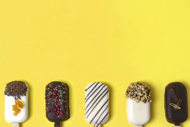 Çikolatalı dondurma. Sarılı dondurma çubuğu, limon arkaplan, pastel renk. Metin için yer, kopyalama alanı.