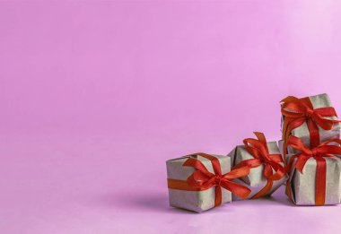 El işi kağıdına sarılı hediye kutuları ve sarı arka planda kırmızı saten kurdele. Bahar, bir kadın için bir hediye, tatil havasından bir hediye. Yeni yıl Noel dekoru. Popüler eğilim.