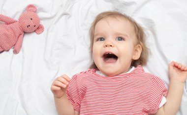 Sırtüstü yatıp gülümseyen mutlu bir kız çocuğu. Mutlu annelik kavramı. Üst görünüm.