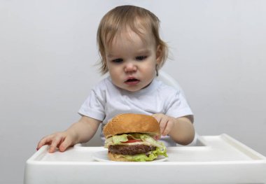 Tatmin olmamış küçük çocuk büyük bir burgerciye bakıyor..