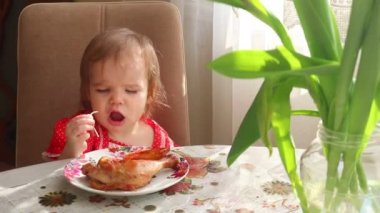 Güzel elbiseli küçük bir kız fırında pişmiş tavuktan küçük parçalar alıp ağzına koyuyor. Bebek bebek festival masasında tavuk eti yiyor.