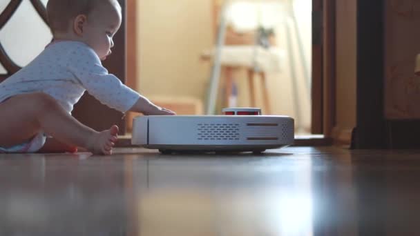 Staubsaugerroboter arbeitet neben einem Baby, das auf dem Boden sitzt — Stockvideo