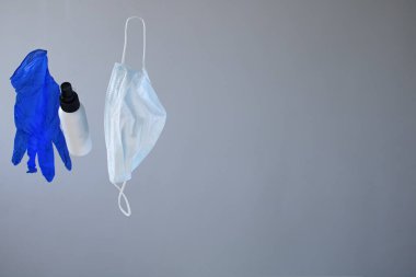 Salgın hastalık koruma kiti, maske yığını, eldivenler ve gri arka planda alkol el dezenfektanı şişesi. Boşluğu kopyala, metin için yer, eğilim