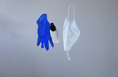 Salgın Hastalıkları Koruma Kiti, maske yığını, eldivenler ve gri arka planda alkol el dezenfektanı şişesi.