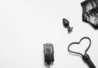 Accessories for bdsm on a white background. Leather handcuffs, butt plug, whip and corset for erotic bed game. Banner, copyspace