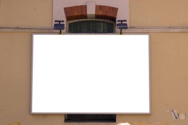 Eski sarı duvarda asılı ilan panosu. Tam ortada..