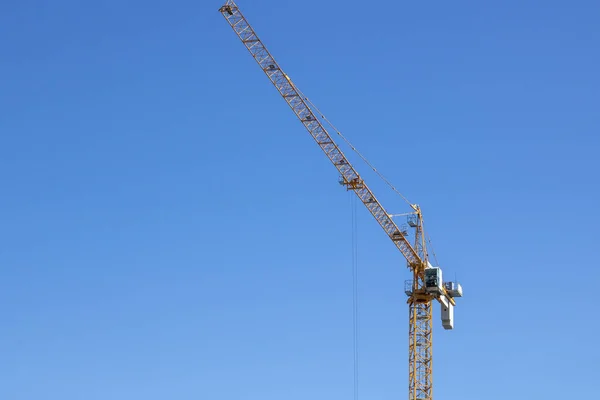 Yellow colored tower crane is being used in construction to lift cargo.