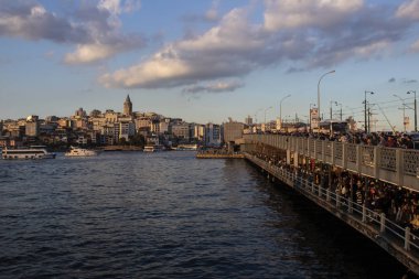 Galata Kulesi ve Galata Köprüsü birlikte ele geçirildi. Galata Köprüsü 'nde balık tutan insanlar. Gün batımında çekilen.