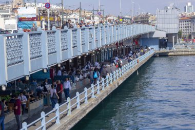 Balıkçılar ve turistler İstanbul 'daki Galata Köprüsü' nde bulunuyor. İstanbul 'un ünlü bir simgesidir. İstanbul 'un tarihi merkezinde birçok insanla Galata Köprüsü.