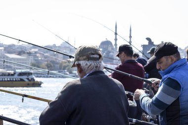 Balıkçılar ve turistler İstanbul 'daki Galata Köprüsü' nde bulunuyor. İstanbul 'un ünlü bir simgesidir. İstanbul 'un tarihi merkezinde birçok insanla Galata Köprüsü.