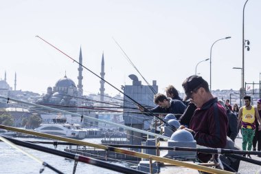 Balıkçılar ve turistler İstanbul 'daki Galata Köprüsü' nde bulunuyor. İstanbul 'un ünlü bir simgesidir. İstanbul 'un tarihi merkezinde birçok insanla Galata Köprüsü.