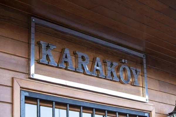 Fuente de color gris sobre superficie marrón madera. Karakoy dice en el cartel . —  Fotos de Stock