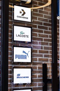 Puma, Converse, Lacoste, Skechers markalarının logoları kapının arkasında asılı..