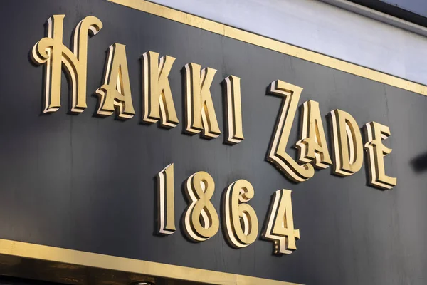 Hakki Zade se estableció en 1864 como pastelero. Cartel de Hakki Zade fotografiado cerca. Color oro sobre superficie negra . —  Fotos de Stock