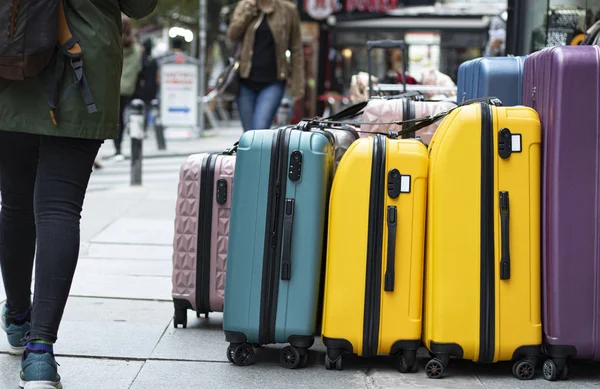 Kaldırımda satılık bavulları kapatın. Farklı renkler ve boyutlarda. İnsanlar kaldırımın önünde yürüyor..