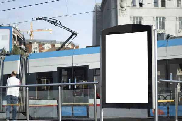 Advertising sign at the tram station stop. The tram passes in the background.