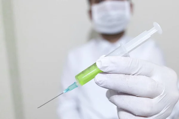 Drží v sobě koronavirovou vakcínu. Vakcína je zelená. Nalevo stojí, že byla nalezena vakcína proti koronovému viru. — Stock fotografie