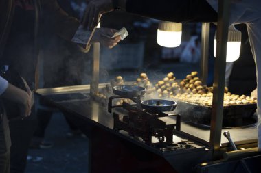 El arabasını haşlanmış mısır ve fırında kestaneyle asan adam. Akşamları çekilmiş..