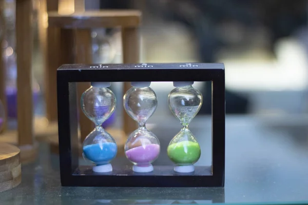 Primer plano de reloj de arena en 3 colores diferentes. En la mesa de cristal. De cerca. . — Foto de Stock