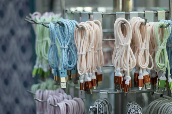 Cables de carga de teléfono trenzados de cerca. Fotografiado frente a la tienda. Colgando. — Foto de Stock