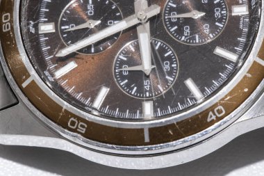 Kullanılmış bir kol saatinin yakın çekimi. Dış kaplama metalik ve içi kahverengi. Makro