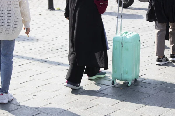 Maleta de color turquesa en manos de un turista. Fotografiado en verano en la calle . — Foto de Stock