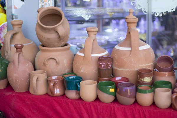 Containers made of clay. Photographed in front of the bench. There are containers, pans, pots of various sizes.