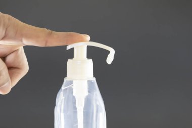 Sıvı sabun şişesinin düğmesine basan bir el. Mikrop ve virüslere karşı el dezenfektanı. Fotoğraf sıvı sabun akarken çekilmiş..