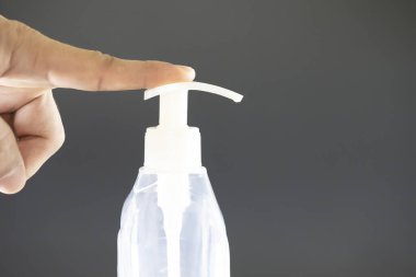 Sıvı sabun şişesinin düğmesine basan bir el. Mikrop ve virüslere karşı el dezenfektanı. Fotoğraf sıvı sabun akarken çekilmiş..
