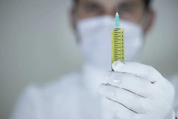 El doctor tiene una vacuna en la mano. Vacunas en colores amarillos. Estudio de rodaje. De cerca. . —  Fotos de Stock