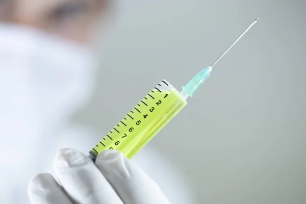Doktorn håller ett vaccin i handen. Vacciner i gula färger. Studioinspelning. Närbild. — Stockfoto