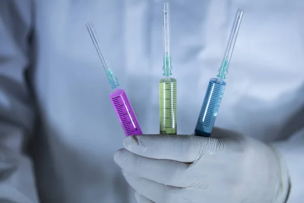 Doktorn håller tre vacciner i handen. Vacciner i röda och gröna färger. Studioinspelning. Närbild. — Stockfoto