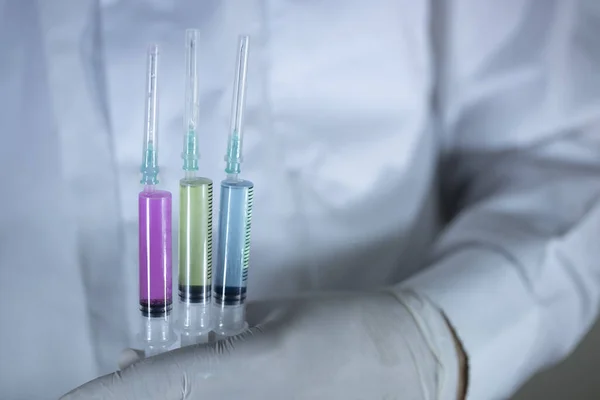 The doctor is holding one vaccines in his hand. Vaccines in purple colors. Studio shooting. Close up. — Stock Photo, Image