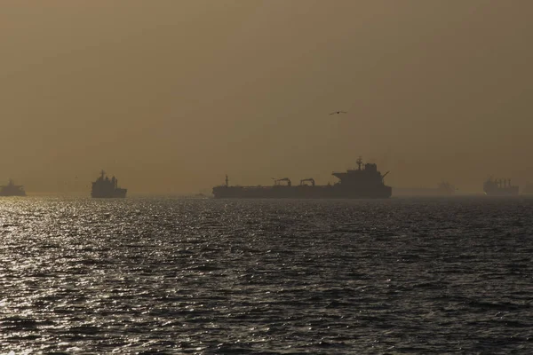 Durante la puesta del sol y la hora dorada en el mar, se ven barcos de transporte . — Foto de Stock