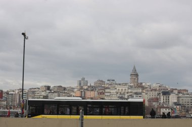 İstanbul, Türkiye - Ocak-Ocak-03.2020: Galata kulesi ve şehir manzarası. Eminonu sahil yolundan geçen sarı şehir otobüsü.