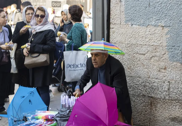 İstanbul, Türkiye - Kasım 05.2019: Sokaklarda yeni şemsiye satan bir adama yakın çekim. Pek çok renk ve çeşitlilik var. Adam duvarın yanında ve etrafında..