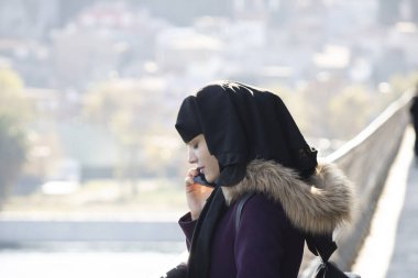 İstanbul, Türkiye - Kasım-02: 2019: Telefonda konuşan güzel Müslüman kadın. Yan taraftan bir fotoğraf çekildi. Açık hava güneşli..