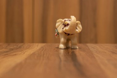 Ahşap desenli bir masada küçük bir fil heykeli var. Kapat..