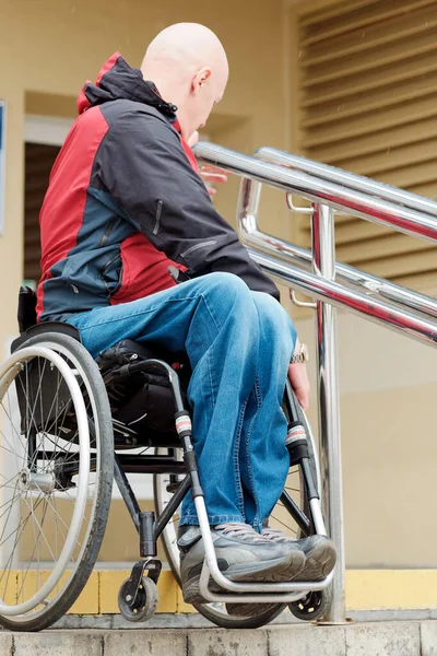 Yazı işleri müdürü, gönüllü eğitmen, tekerlekli sandalyedeki ve kentsel alandaki engelsiz ortamda basamakları ve engelleri aşma tekniğini gösteriyor.