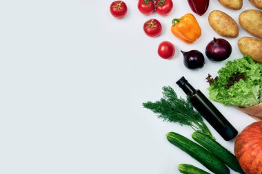 Bakkaliye: kabak, patates, domates, kırmızı soğan, kırmızı ve sarı dolma biber, salatalık, dereotu, marul, beyaz arka planda bir şişe zeytinyağı.