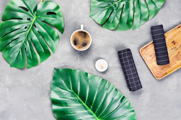 Taza de café con hojas tropicales sobre fondo gris . — Foto de Stock