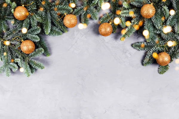 Рождественский бетонный фон с елкой и золотыми игрушками и огнями. — стоковое фото