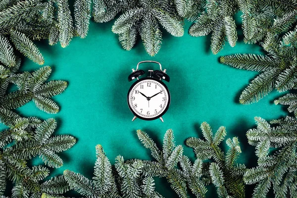 Relógio preto no fundo verde com ramos de Natal . — Fotografia de Stock