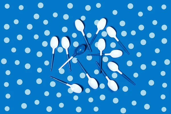 White plastic spoons on blue background. — ストック写真