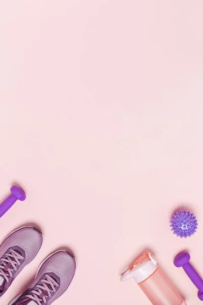Kadın eğitimi için spor aletleri ve ayakkabılar. Pembe arkaplan, dikey resim.