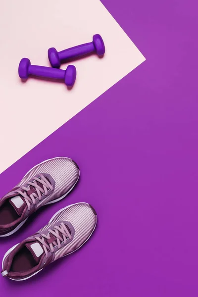 Kadın eğitimi için spor aletleri ve ayakkabılar. Pembe arkaplan, çapraz kompozisyon.