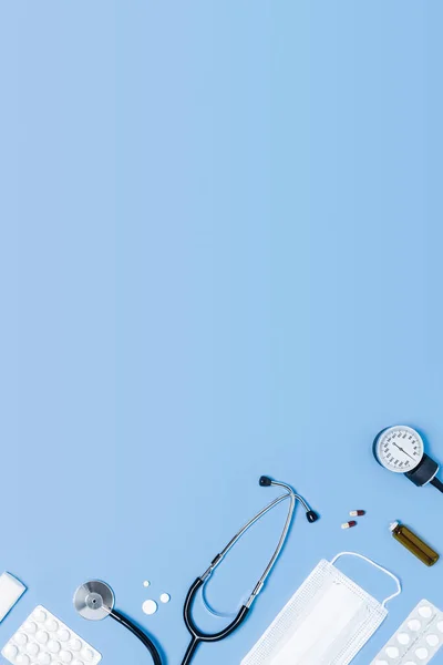 Medical blue vertical background with different accessories: stethoscope, thermometer, syringe and tablets.