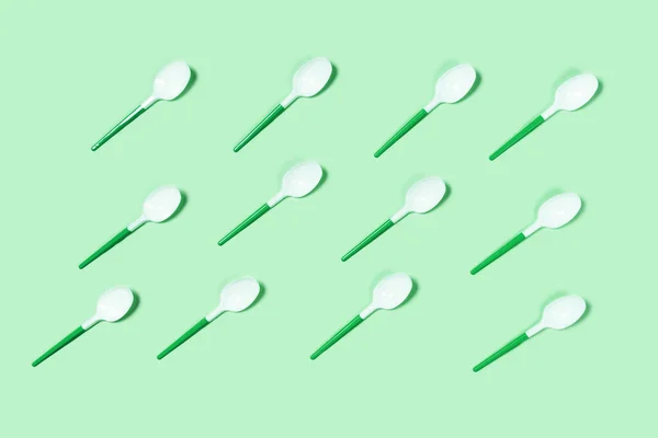 White plastic spoons on green background. — Stock Photo, Image