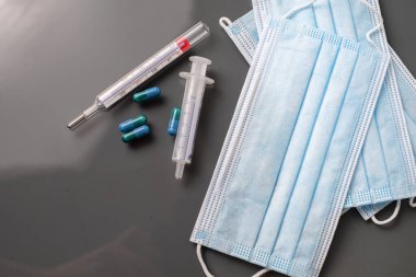 Tıbbi kapsüller ve beyaz arka planda termometre.